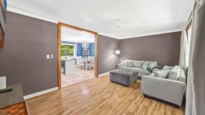Una sala de estar moderna con un sofá gris, un reposapiés y piso de madera.