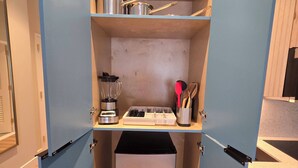 A compact kitchen with a built-in refrigerator, a blender, and a utensil holder.