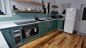 Una cocina con armarios azul verdoso, un refrigerador blanco y piso de madera.