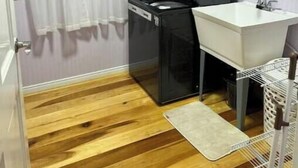 Una cocina compacta con refrigerador, pileta y piso de madera.