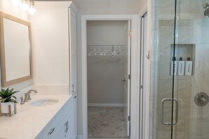 A bathroom with a sink, mirror, and shower.