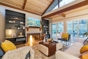 Una sala de estar moderna con chimenea, estanterías empotradas y un ventanal con vistas a una terraza.