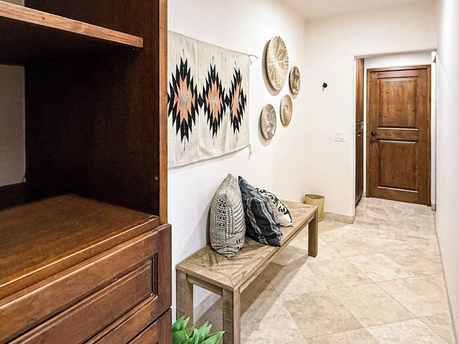 Un couloir avec un banc en bois, une œuvre d’art accrochée au mur et une porte.