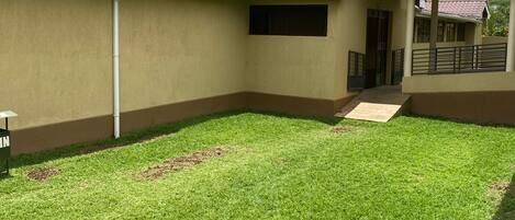 A building with a flat roof, a covered walkway, and a grassy courtyard.