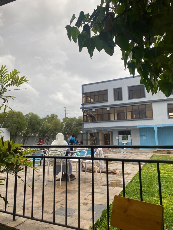 A courtyard with a pool, outdoor seating, and a building with multiple windows. - Lake Naivasha Lazurus Lodge (Naivasha)