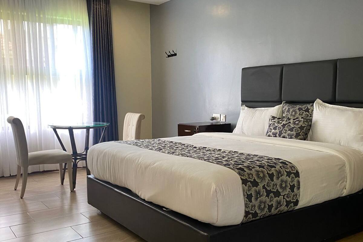 A hotel room with a large bed, a chair, a small table, and a nightstand.