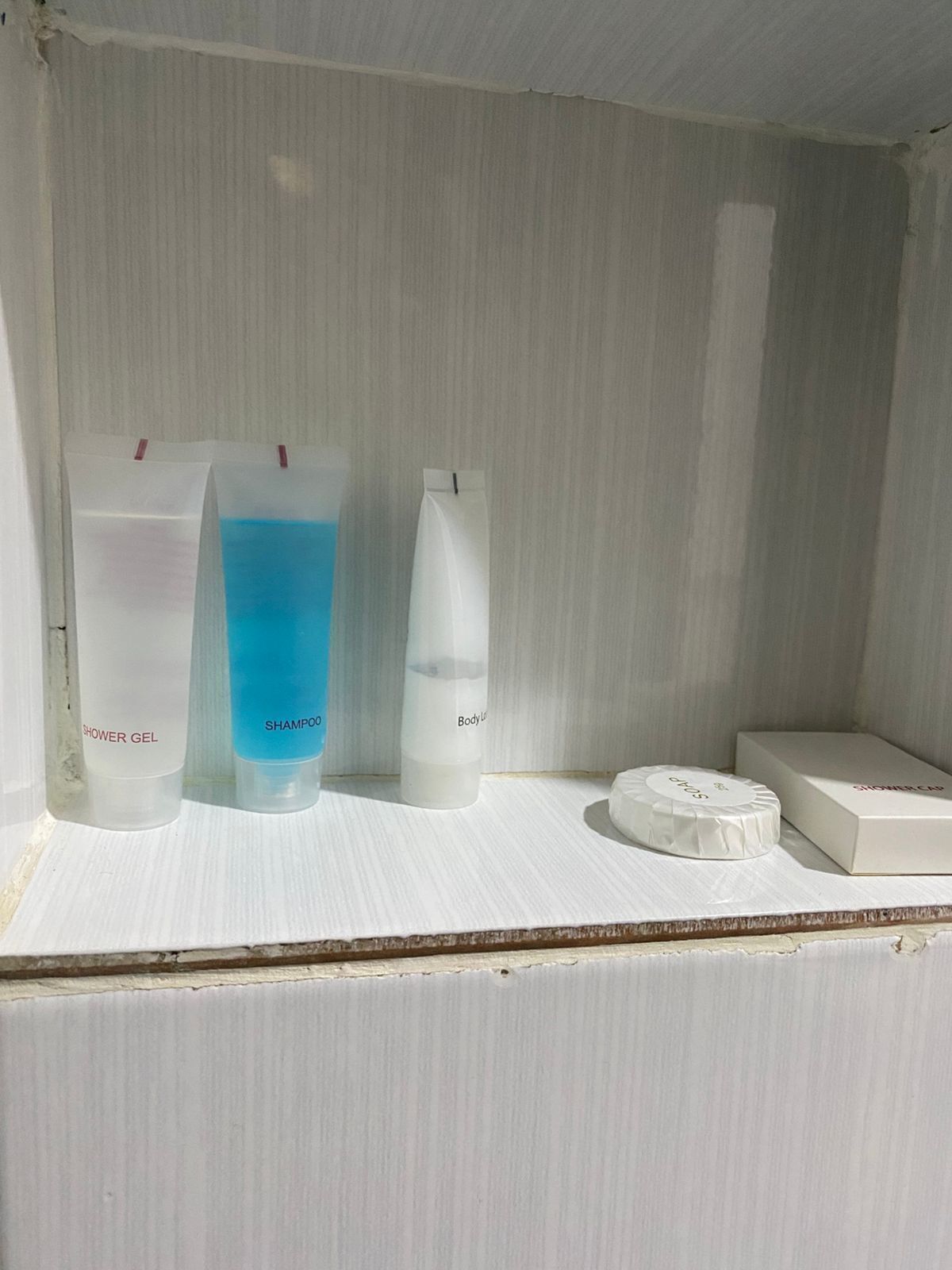 Une étagère de salle de bain avec trois flacons de produits de toilette et un savon.