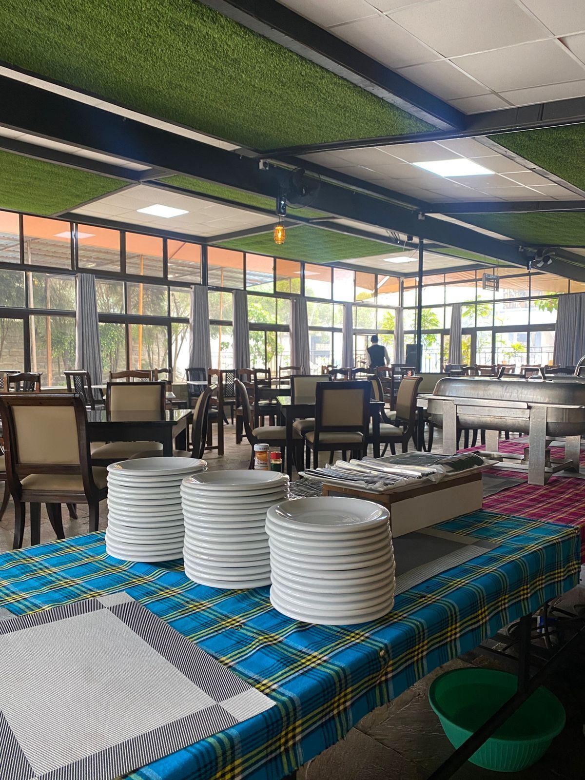 A restaurant with a green ceiling, large windows, and a table set with plates and bowls.