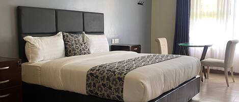 Una habitación de hotel moderna con una cama grande, un escritorio, una silla y una mesita.