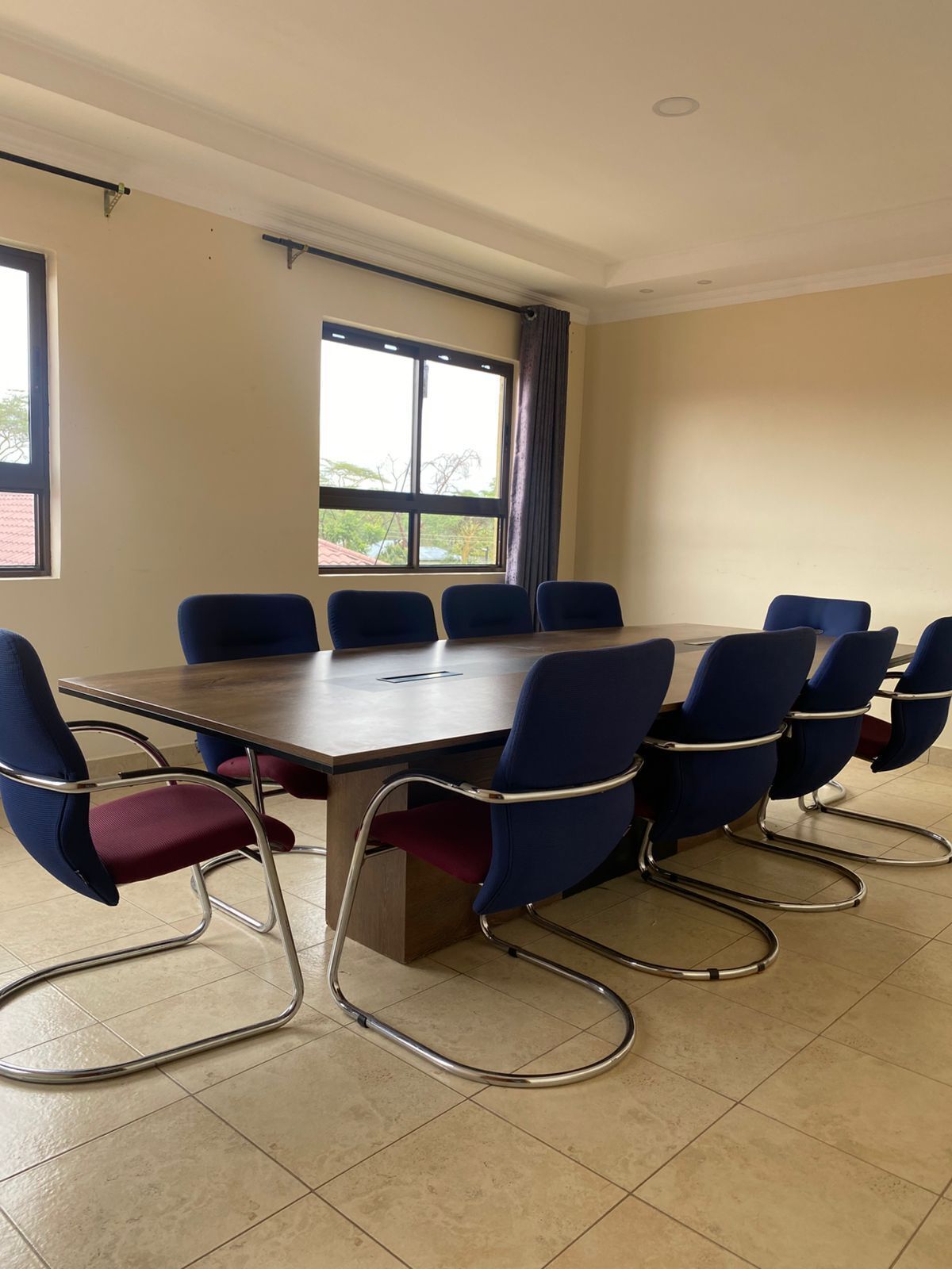 A conference room with a long table and eight blue chairs.