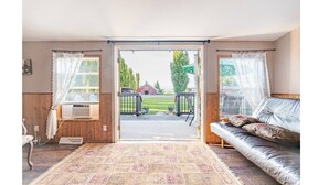 A room with a sofa, a radiator, and a view of a barn and trees.