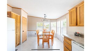 A kitchen with wooden cabinets, a dining table with chairs, and a chandelier.