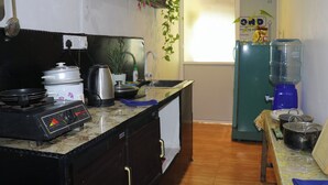 Eine kleine Küche mit einem Gaskochfeld, einem Wasserkocher, einem Mixer und einem Kühlschrank.
