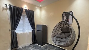 A room with a marble floor, a black refrigerator, a hanging chair, and curtains. - Smart 2-bedroom bungalow in lovely Egbeda with WiFi, AC,parking space,games etc… (Egbeda)