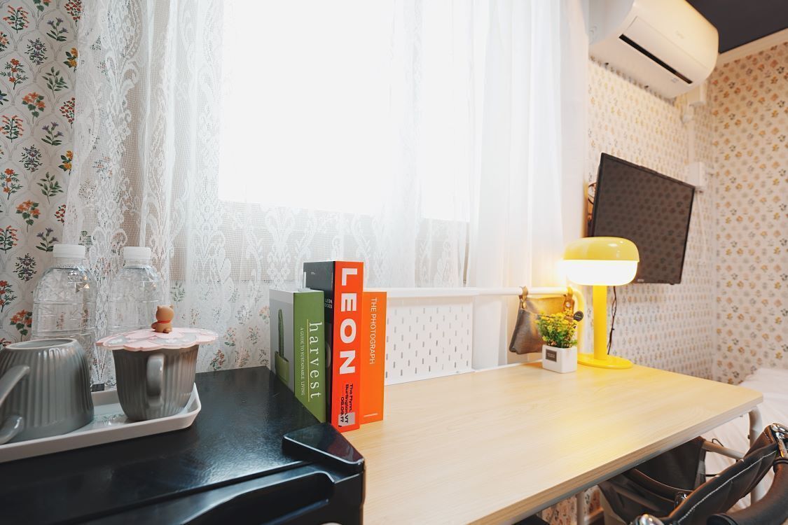 A neatly arranged desk with a tray of mugs, a lamp, and a selection of books.