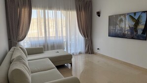 Un salón amplio con un sofá grande, una mesa de centro y un cuadro de una playa.