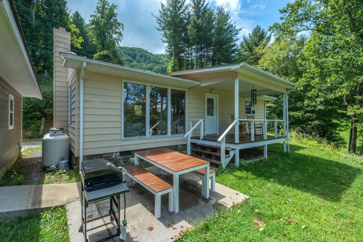 A two-story house with a porch, a grill, and a patio table.