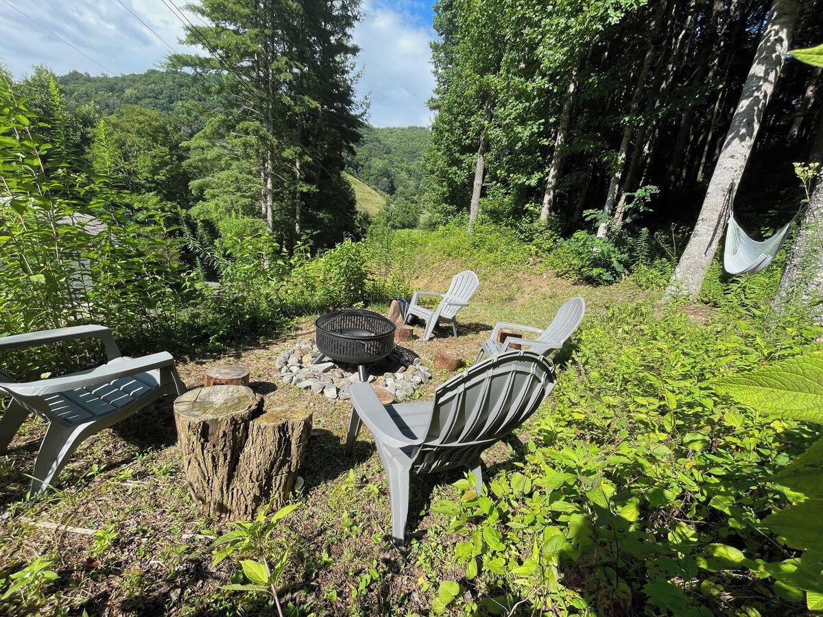 An outdoor seating area with a fire pit, chairs, and a hammock.