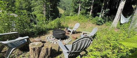 An outdoor seating area with a fire pit, chairs, and a hammock.