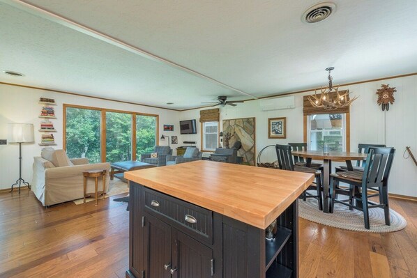 A spacious kitchen with a wooden island, dining area with chairs, and a ceiling fan.