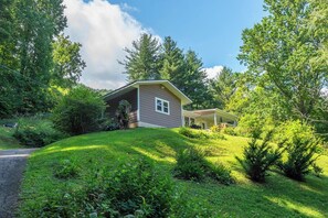 Ein Haus mit einer überdachten Veranda, umgeben von üppigem Grün und Bäumen.