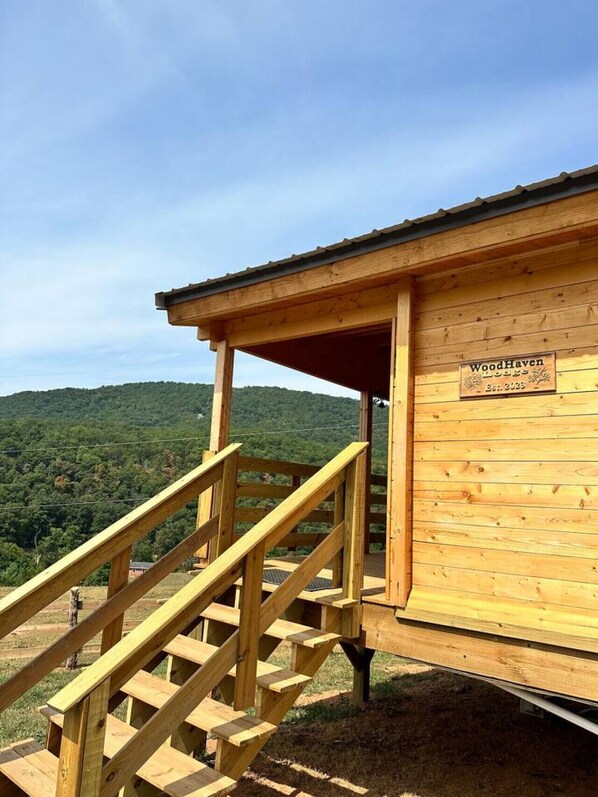 Una cabaña de madera con una escalera de madera que conduce hacia ella, rodeada de un paisaje boscoso.