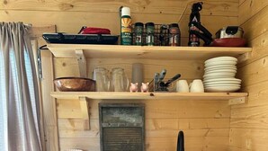 Cocina pequeña con armarios de madera, un lavamanos, una cafetera y un cubo de basura.