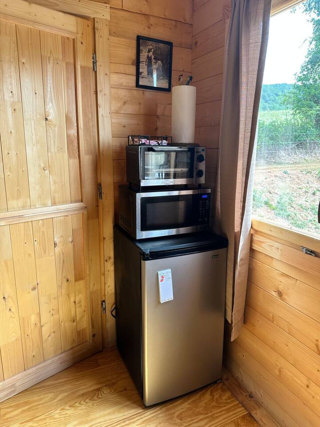 A compact kitchenette with a stainless steel refrigerator, a microwave, and a toaster oven.