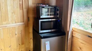 A compact kitchenette with a stainless steel refrigerator, a microwave, and a toaster oven.