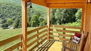 Una terraza de madera con un banco y una lámpara colgante.