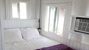 A room with a bed, a window, and an air conditioning unit. - Cocolobba Cottage by the Sea in Whale Point (Upper Bogue)
