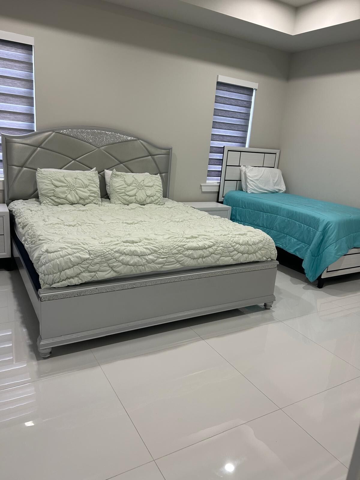 A bedroom with a large bed, a smaller bed, and a nightstand.