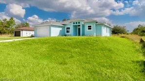 Une maison de plain-pied à la façade bleu clair, avec un garage et une pelouse bien entretenue.