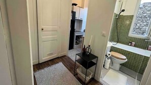A compact bathroom with a toilet, sink, and shower area. - Cosy near the Eiffel Tower (Paris)
