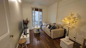A living room with a sofa, a coffee table, a side table, and a decorative tree light. - Cosy near the Eiffel Tower (Paris)