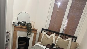 A bedroom with a bed, bedside table, dresser, and a fireplace. - Cosy near the Eiffel Tower (Paris)