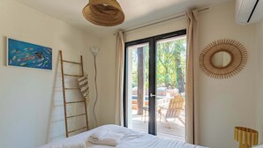 Un dormitorio con cama, un cuadro, una escalera y vistas al exterior.