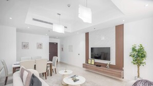 A modern living room with a flat-screen TV, a dining area with a table and chairs, and a seating area with sofas and a coffee table. - StayShort - Spacious 2-Bed Al Barsha Escape - Balcony & Modern Amenities, Fits 4 (Al Barsha 1)