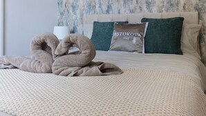 Ein Hotelzimmer mit einem Bett, einem Kopfkissen mit dem Aufdruck 'ESTOKOVA stay' und einer dekorativen Handtuchgestaltung.