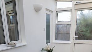 Ein modernes Wohnzimmer mit einem beigen Sofa, einer Decke und einer Vase mit Blumen.