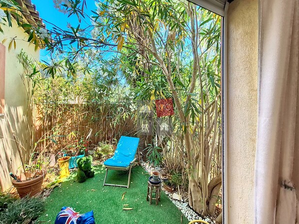 A small garden with a blue lawn chair, potted plants, and a small table. - VILLA LES GOONYS (Le Plan-de-la-Tour)