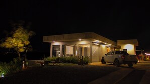 A modern house with a driveway, a parked car, and a well-lit exterior.