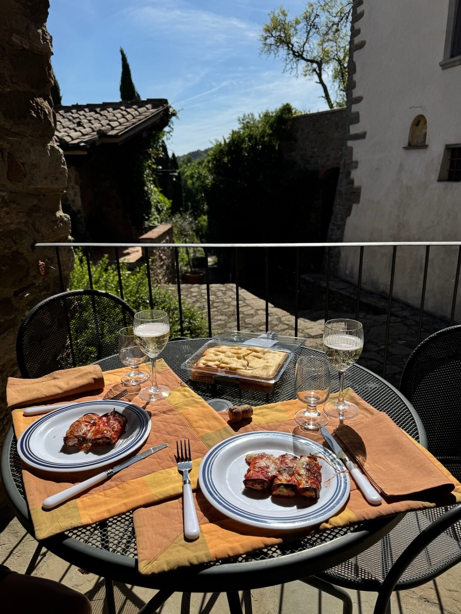 Ein Essplatz im Freien mit Speisen, Weingläsern und einer Dessertplatte.