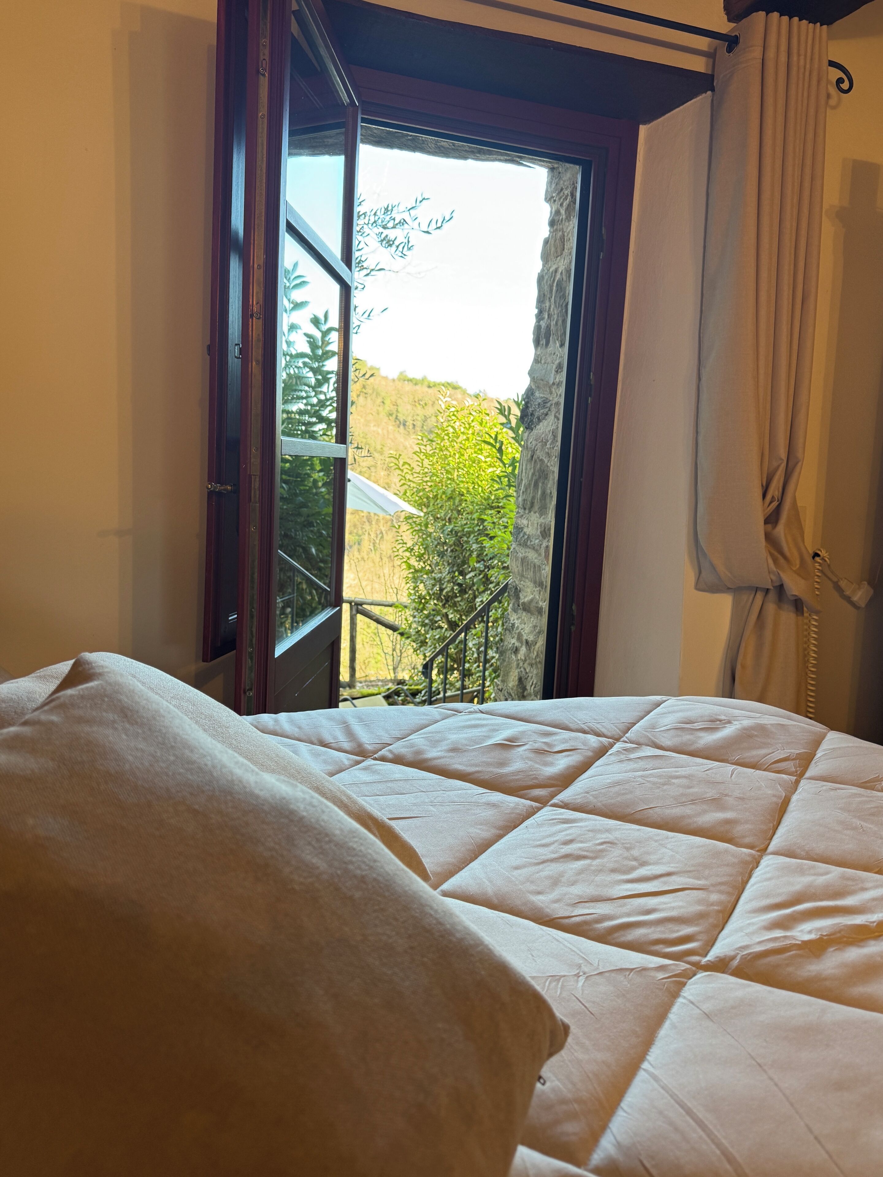 Un dormitorio con cama, ventana que ofrece vista a follaje y una escalera.