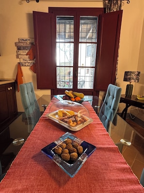 A dining table with a red tablecloth, two chairs, and a glass-top table. There are plates of food and a bowl of nuts on the table.