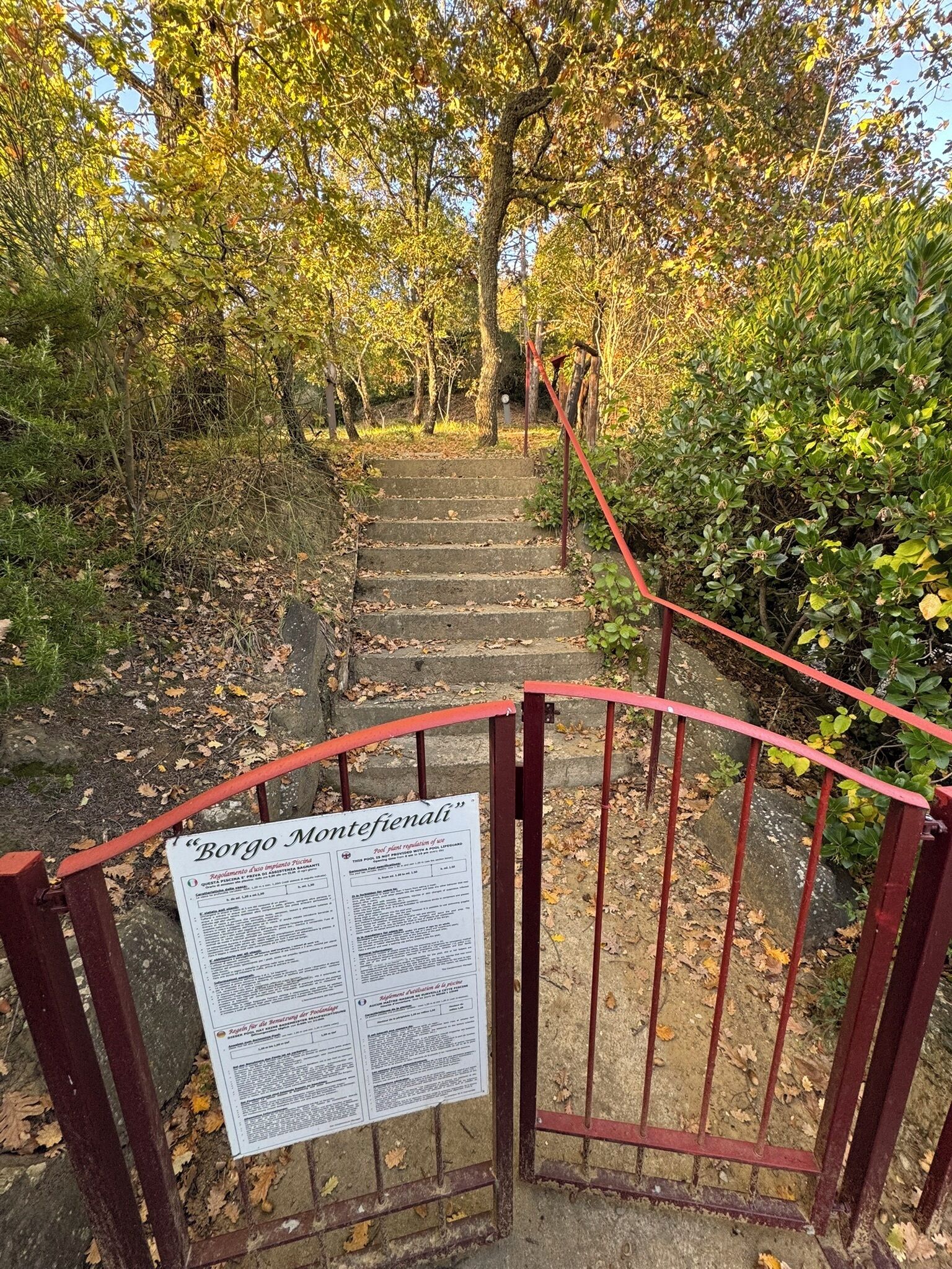 Un escalier en pierre mène à une porte sur laquelle est apposée une plaque indiquant « Borgo Montefienali ».