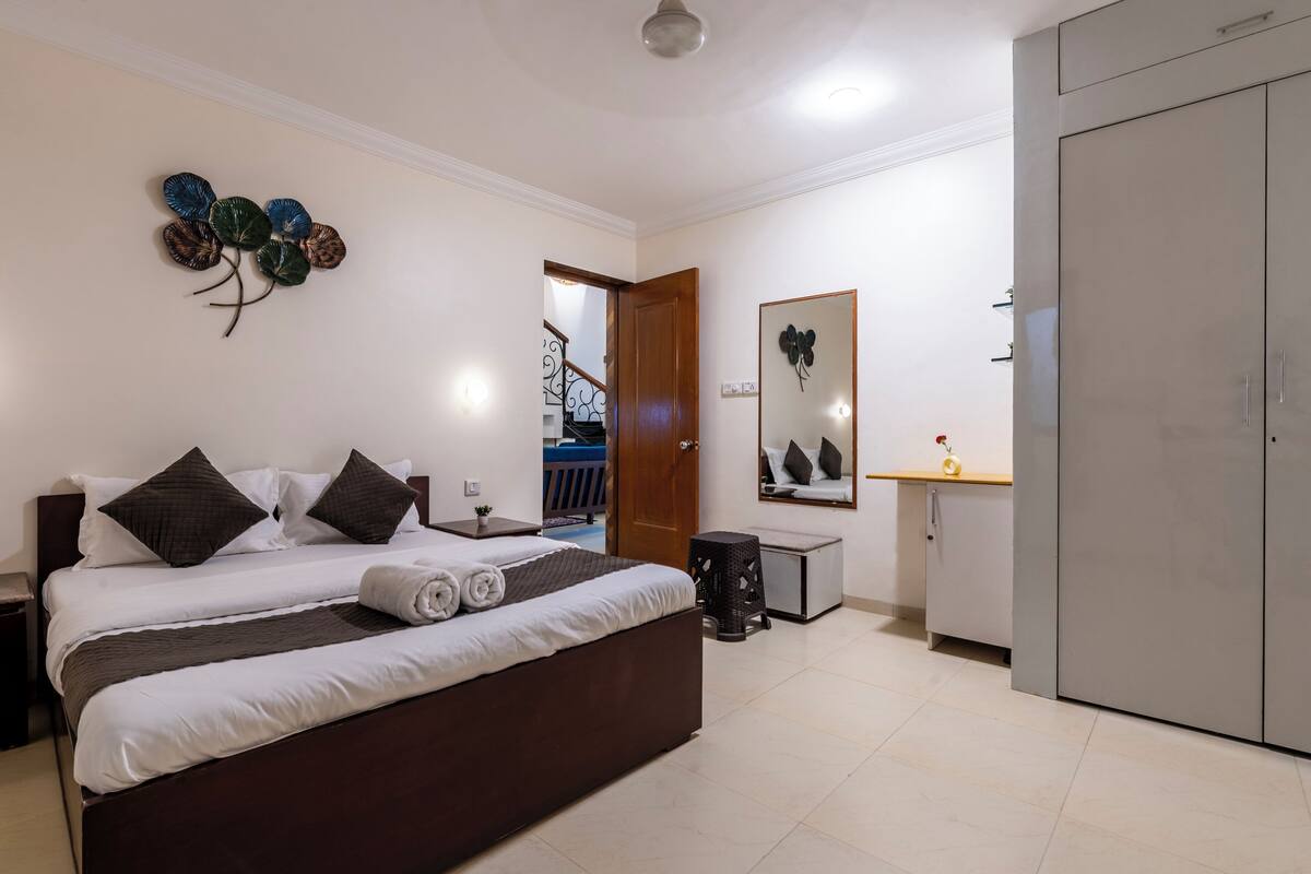 Quarto com cama grande, guarda-roupa, espelho e decoração na parede.