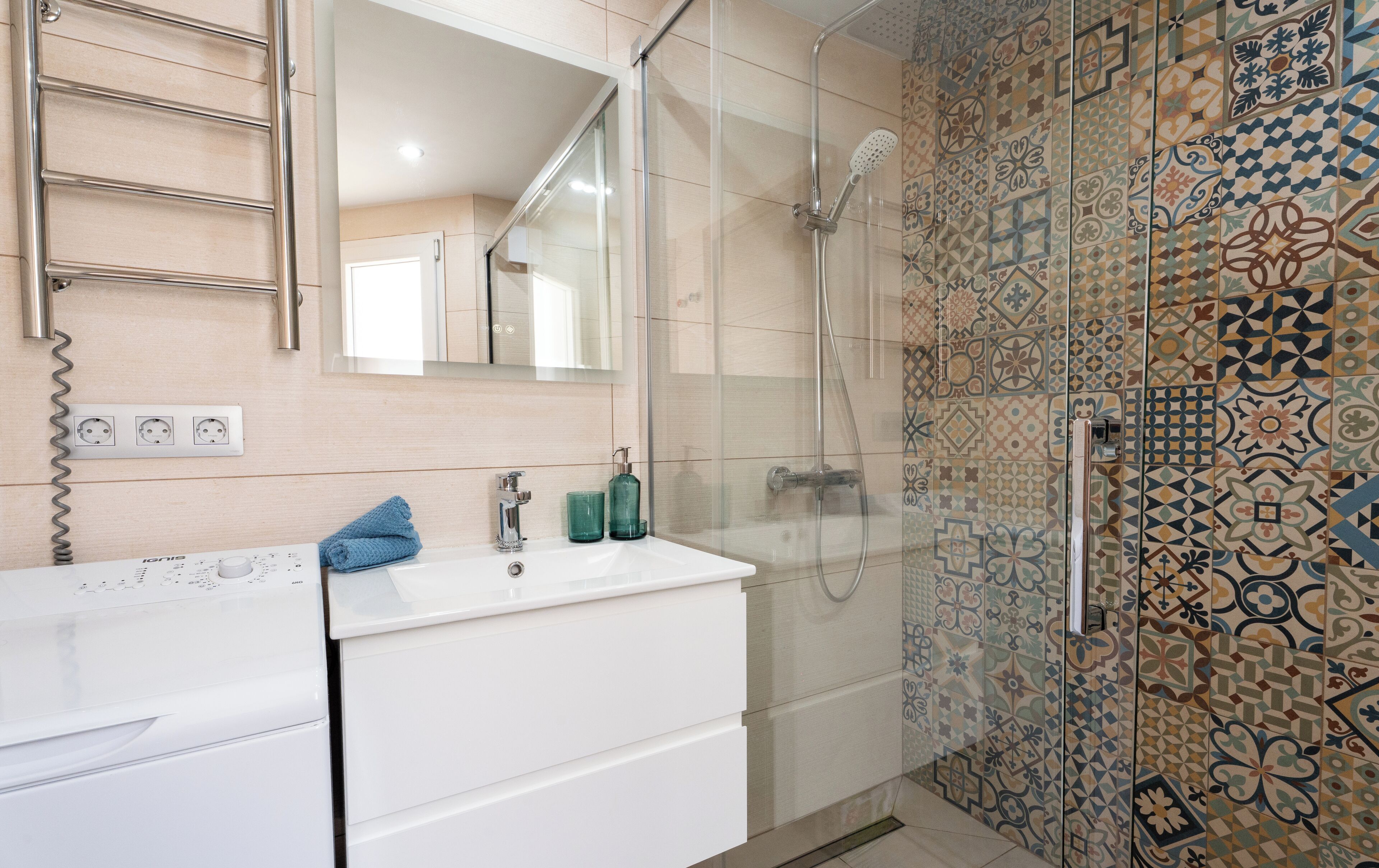 A modern bathroom with a white vanity, a glass-enclosed shower, and patterned tiles.