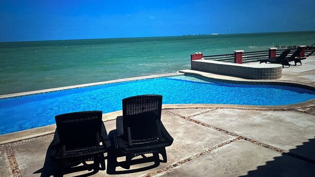 A swimming pool with two lounge chairs and a view of the ocean. - Your Private Beachfront Retreat in Chelem, Yucatán (Chelem)