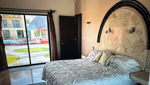 A bedroom with a large bed, a view of a swimming pool, and a door leading to an outdoor area. - Your Private Beachfront Retreat in Chelem, Yucatán (Chelem)